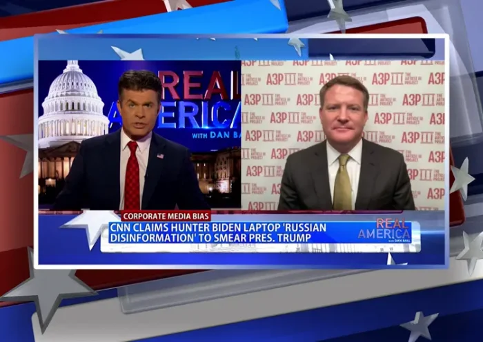 Video still from Real America on One America News Network showing a split screen of the host on the left side, and on the right side is the guest, Mike Davis.