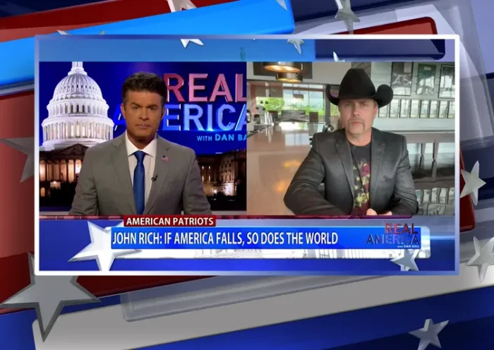 Video still from Real America on One America News Network showing a split screen of the host on the left side, and on the right side is the guest, John Rich.