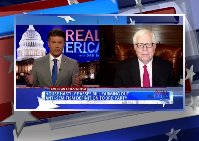 Video still from Real America on One America News Network showing a split screen of the host on the left side, and on the right side is the guest, Dennis Prager.