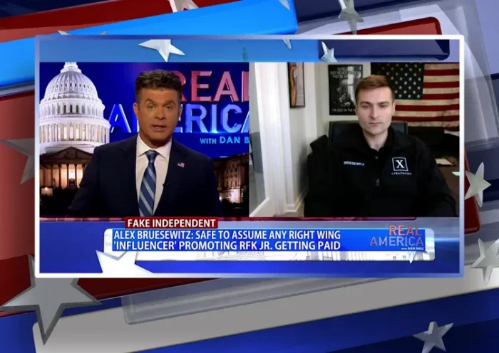 Video still from Real America on One America News Network showing a split screen of the host on the left side, and on the right side is the guest, Alex Bruesewitz.