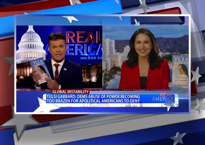 Video still from Real America on One America News Network showing a split screen of the host on the left side, and on the right side is the guest, Tulsi Gabbard.