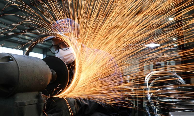 Worker wearing a face mask works on a production line manufacturing bicycle steel rim at a factory in Hangzhou, Zhejiang